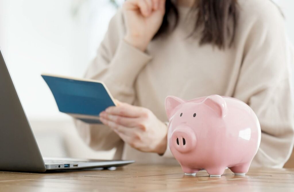 A pink piggybank sits next to a laptop as a patient worries over their insurance coverage