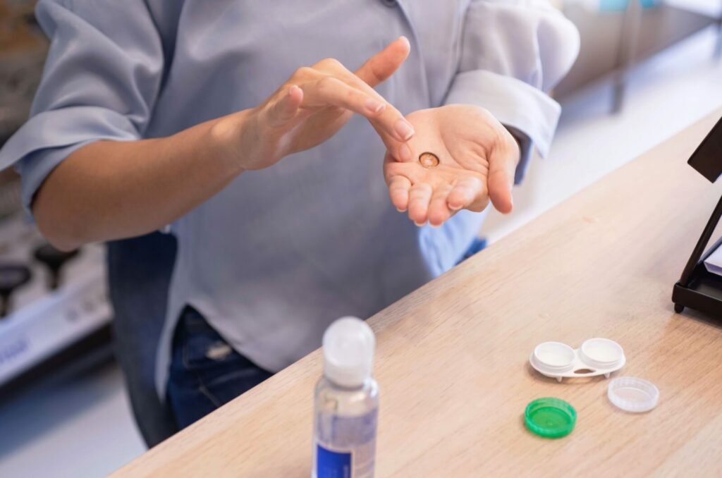 An individual holds a contact lens in their palm before cleaning it with appropriate cleaning solution.