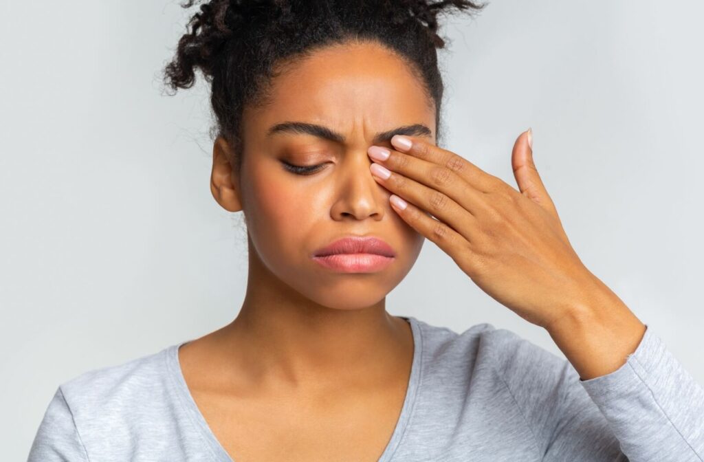 A frustrated person covers one of their eyes, potentially due to blepharitis symptoms.
