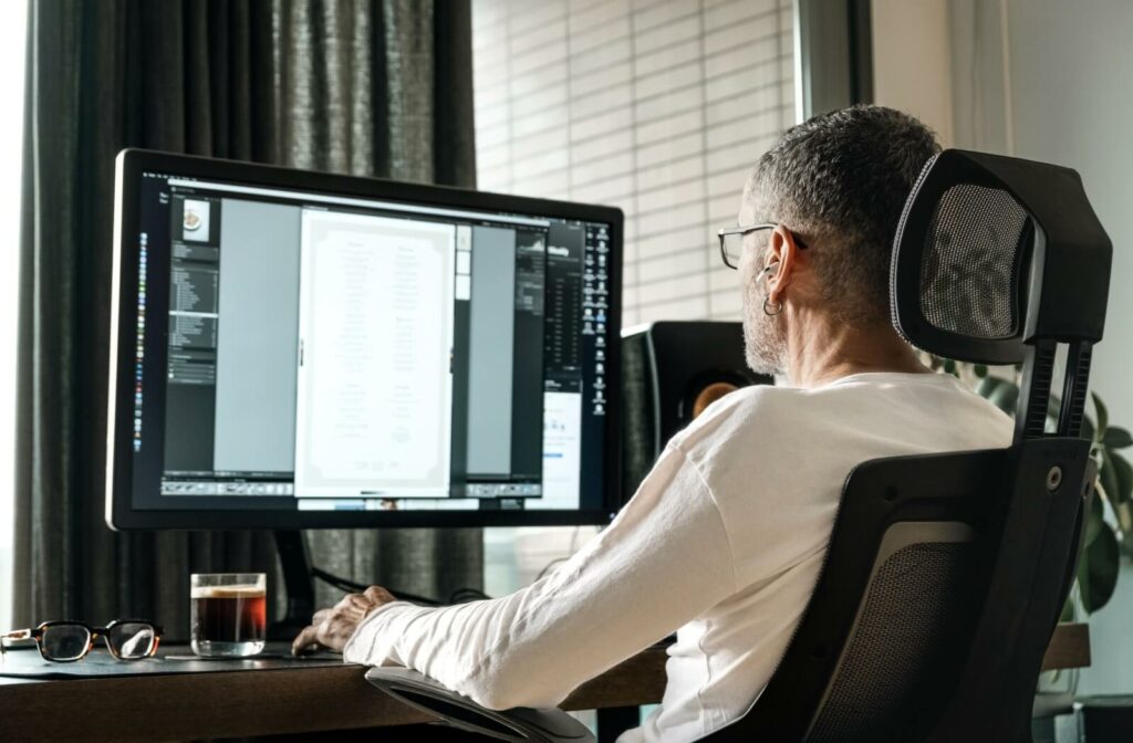 A person sits comfortably at their desk, with their computer screen at eye level and an arm's length away.