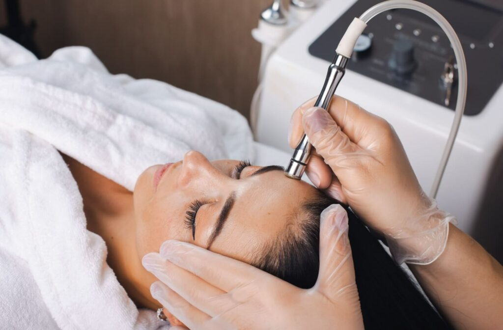 A technician carefully maneuvers the microdermabrasion device on a patient's skin during their treatment session.